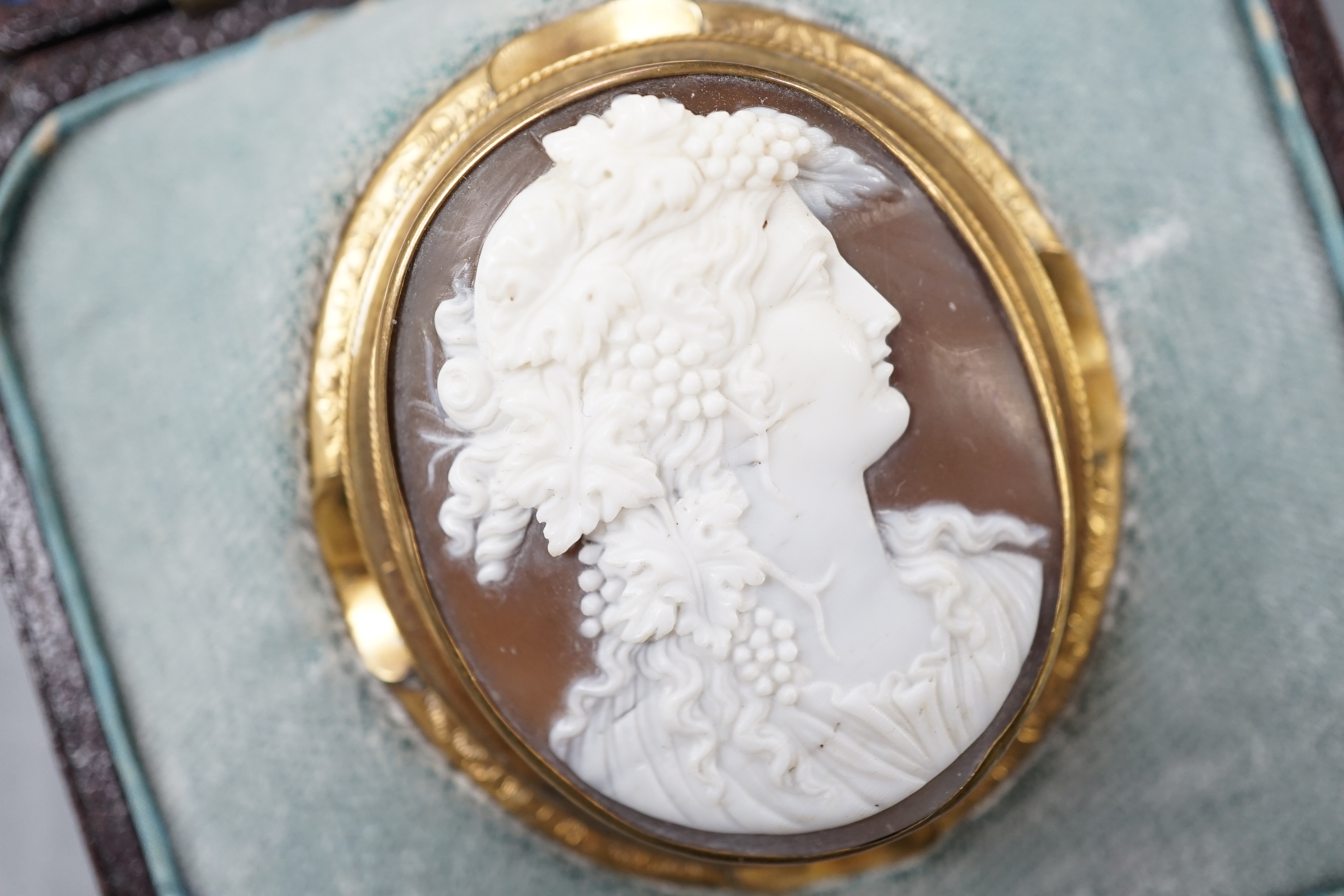 A cased Victorian yellow metal mounted oval cameo shell brooch, carved with the bust of a lady to sinister, 50mm, gross 15.6 grams.